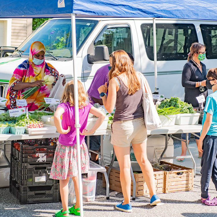 people shopping at the Liberation farms stall at farmers market