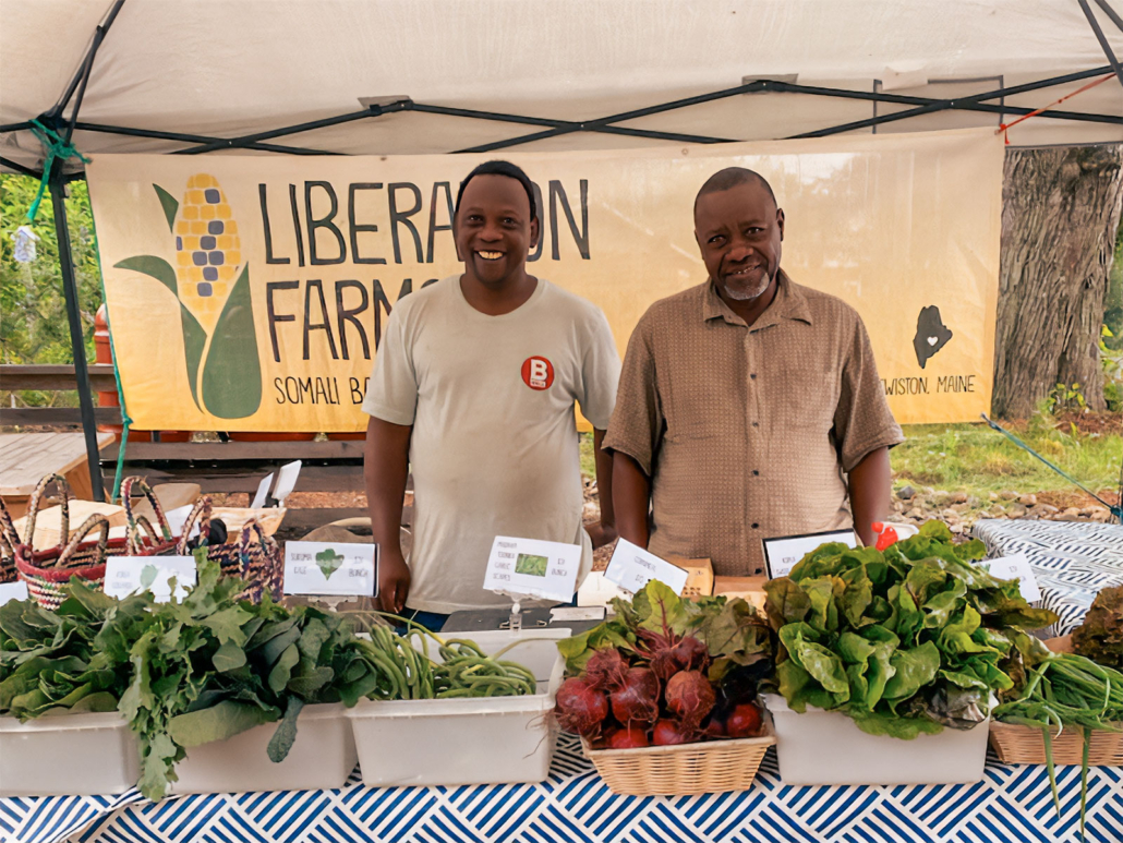 Two farmers proudly selling fresh produce at Liberation Farms market